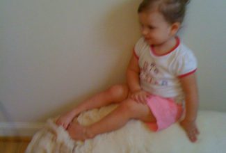 Little girl sitting happily on the back of a golden retriever.